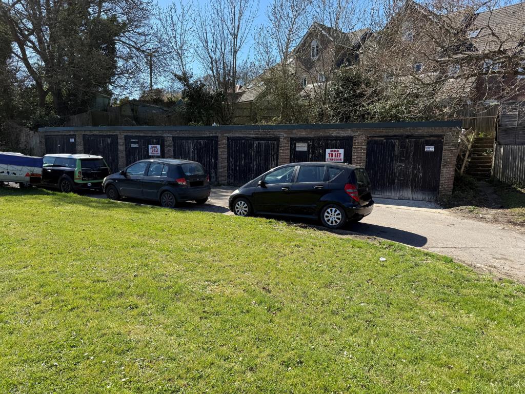 Lot: 33 - FREEHOLD BLOCK OF SEVEN GARAGES WITH POTENTIAL - Front view with parking and grass verge